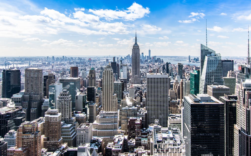 A stunning aerial view of New York City's skyline featuring the iconic Empire State Building under a bright blue sky.