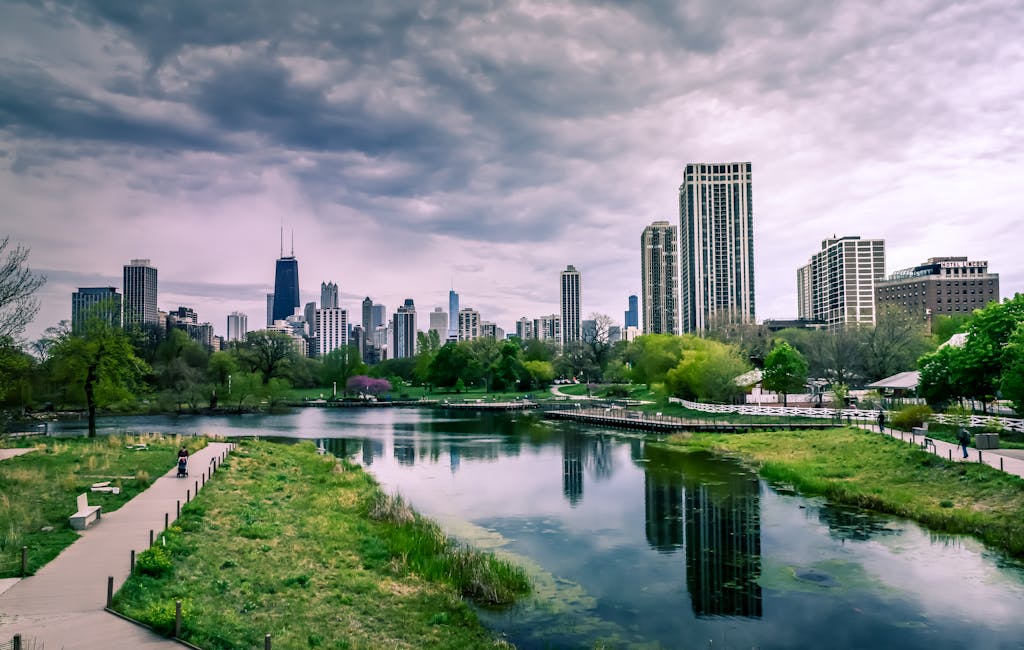 Dramatic view of Chicago skyline with reflections over Lincoln Park Lagoon on a cloudy day.